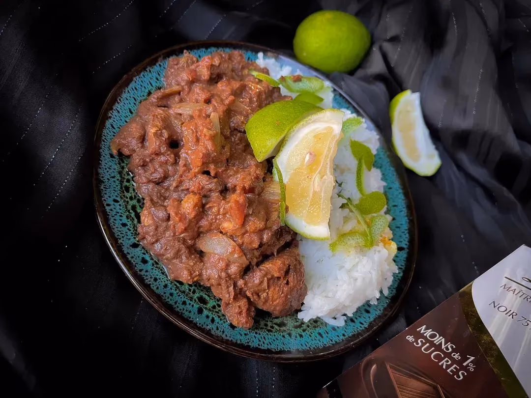Dans un petit bol se trouve du poulet émincé mélangé avec les différents ingrédients qui composent la sauce chocolat. Du riz blanc accompagne le tout.