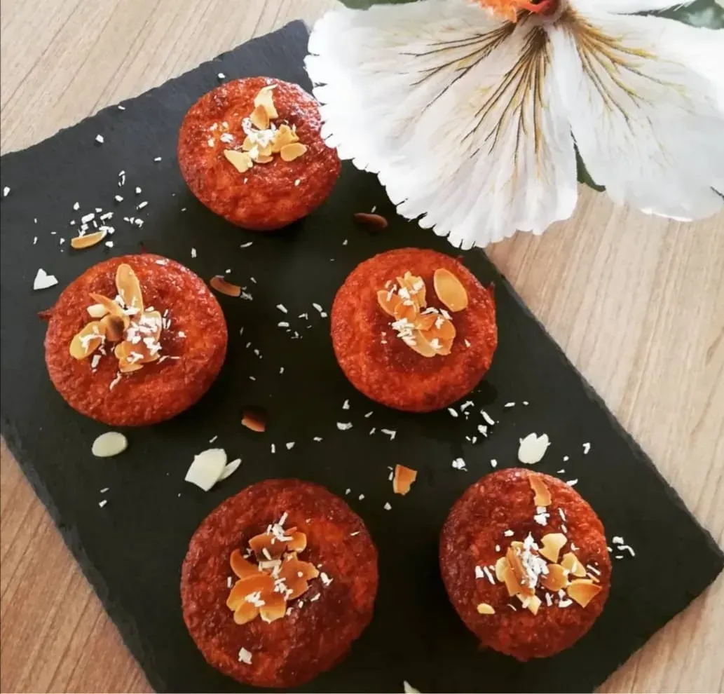 Still resting on the baking sheet are five nicely golden muffins. The topping is made of small sliced almonds.