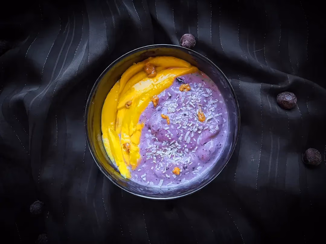 In a small blue bowl, you can see the beautiful blend of colors between the blueberries and the mangoes.