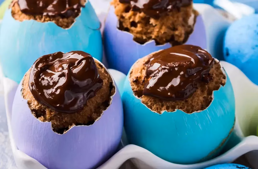Quatre coquilles d'oeufs joliment peintes reçoivent la préparation avec sur le dessus du chocolat brillant.