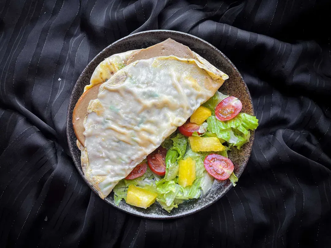 A small blue bowl holds the Asian-style layered omelet with its rice paper.