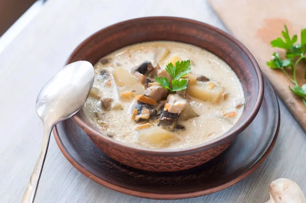 In a large brown bowl is the one-pot potato, curry, and soy dish. It looks like a kind of soup.