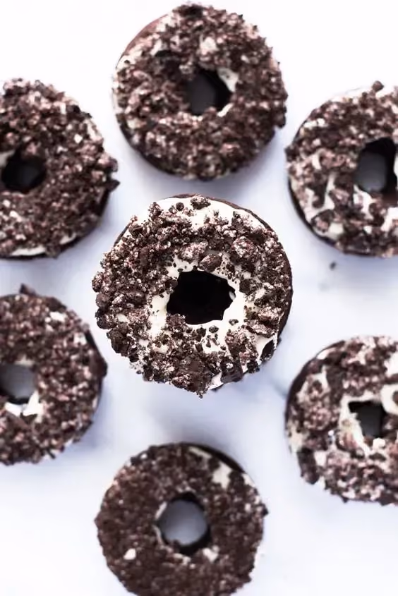 Sept Oreos cookies donuts sont posés sur un plan de travail de couleur blanc.