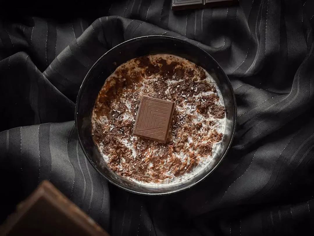 L'overnight aux graines de chia façon Bounty est présenté dans un bol de couleur bleu. Un carré de chocolat sert de topping.