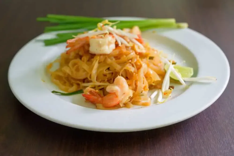 In a deep white plate is the Pad Thai, with shrimp, konjac noodles, and bean sprouts.