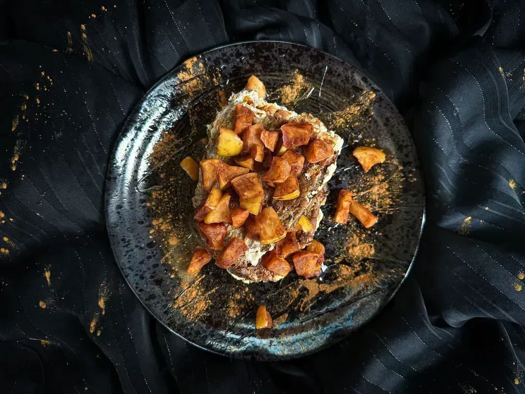 A small blue earthenware bowl holds the apple and cinnamon French toast recipe.