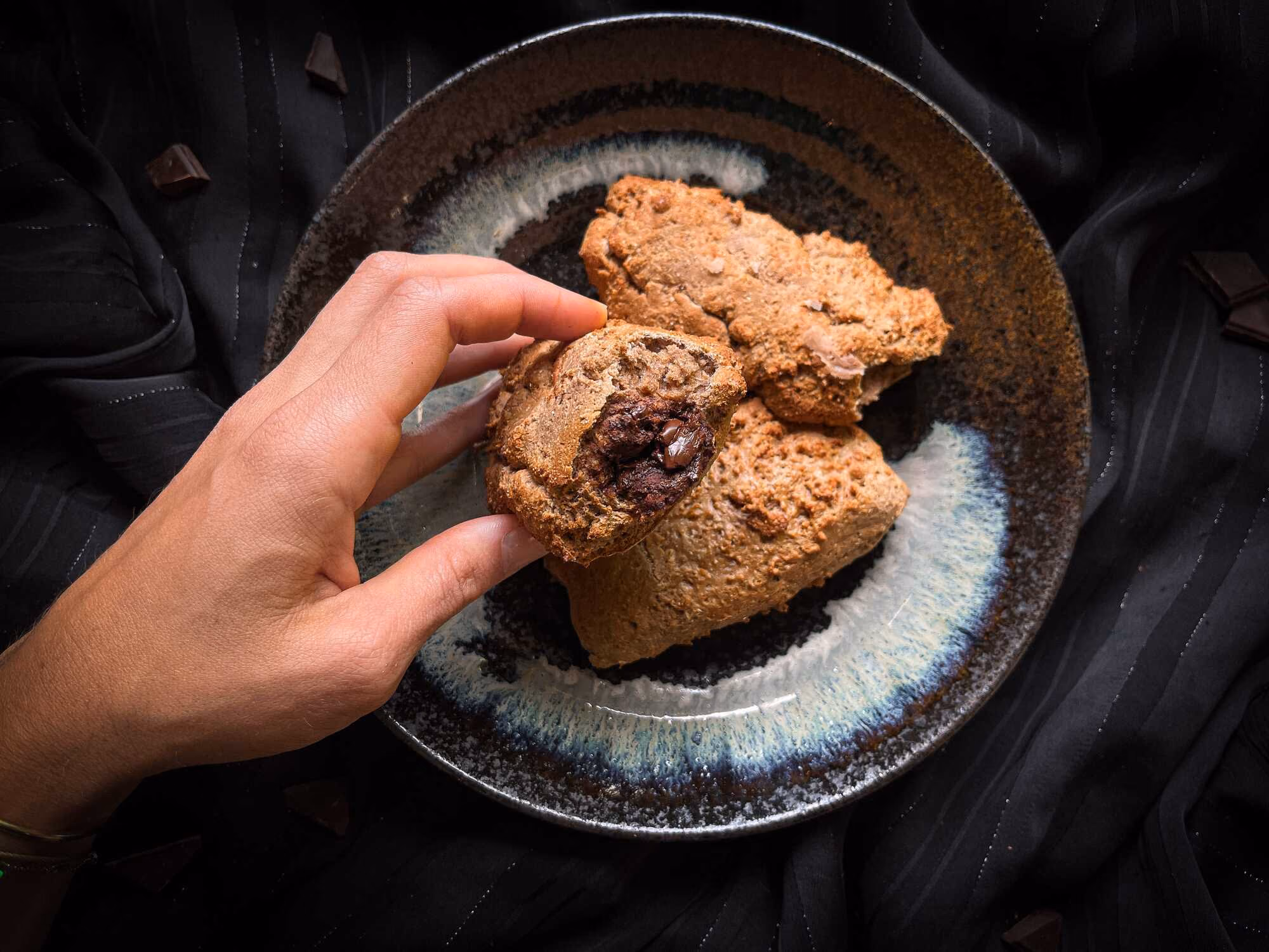 Three beautiful pieces of chocolate-filled protein bread are presented in a small blue dish. Maëlle is holding one piece in her hand.