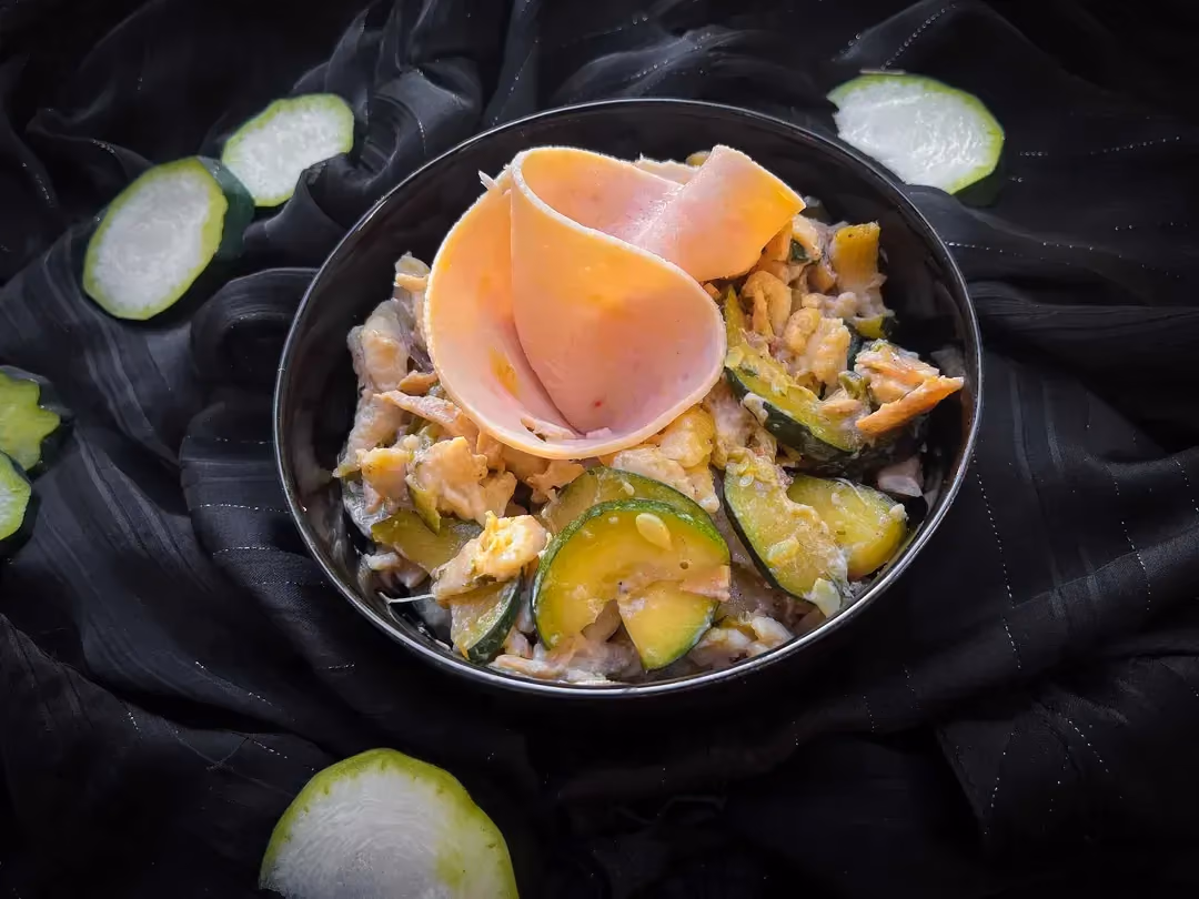 Dans un saladier se trouve la recette de Spaetzle aux courgettes et blanc de dinde. Sur le dessus il y a une tranche fine de blanc de dinde enroulée.