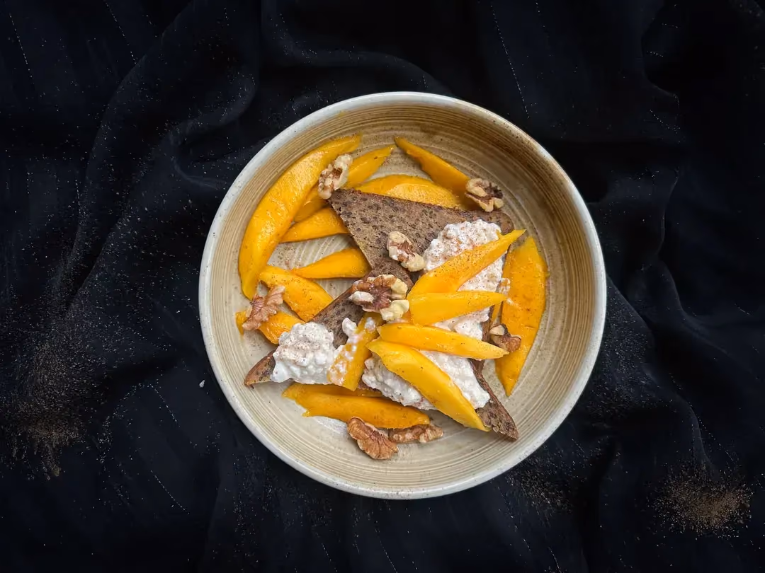 La recette de tartines au cottage cheese et mangues est présentée dans un bol en grès de couleur beige.