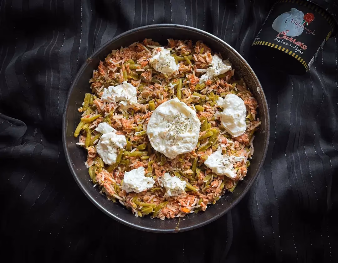 In a small bowl, there is tuna with arrabbiata sauce, ruz, green beans, and burrata.