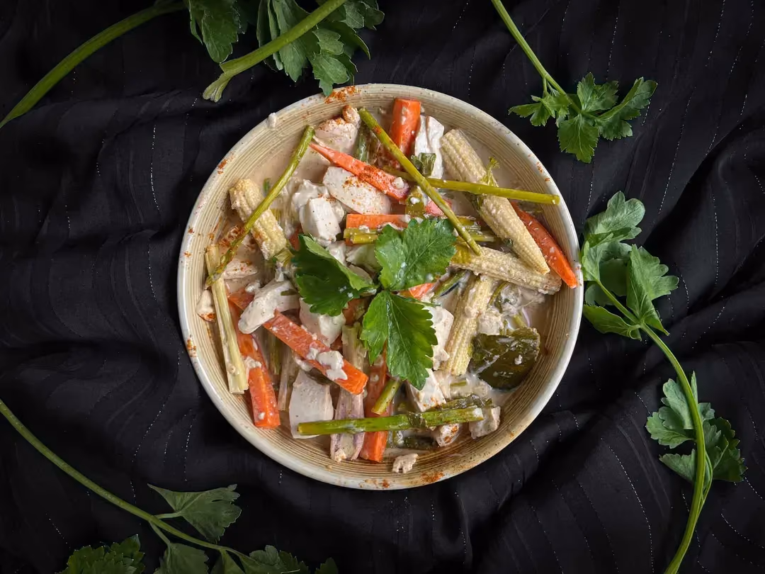 A stoneware bowl holds the Tofu with coconut milk, lemon, combava, and lemongrass recipe. Chopped cilantro is on top.