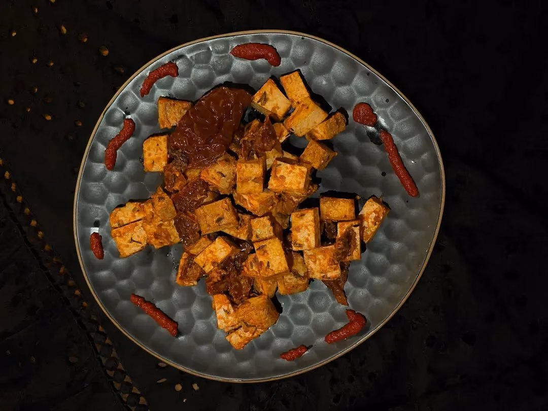 In a small blue bowl with an uneven rim, you can see marinated tofu with sun-dried tomatoes.
