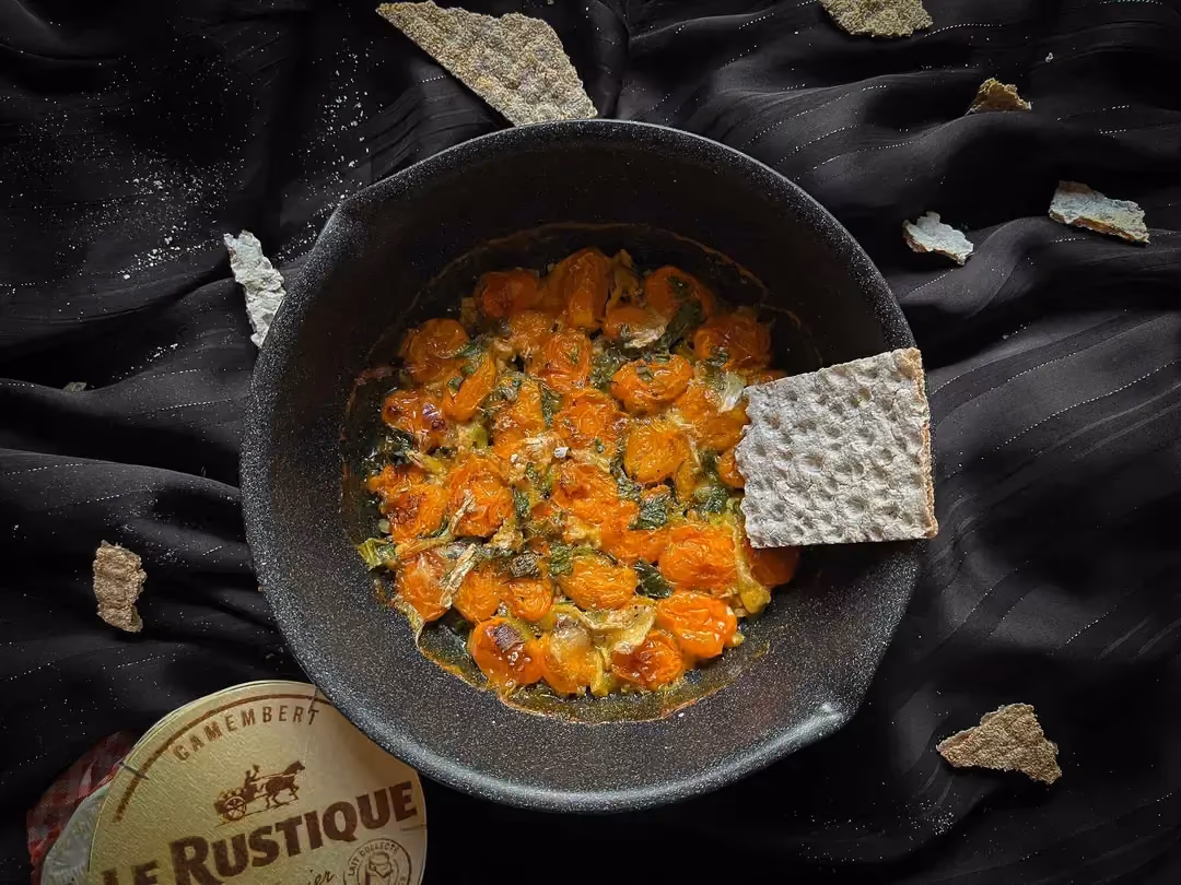 A stoneware bowl holds the recipe for oven-roasted cherry tomatoes and Camembert.