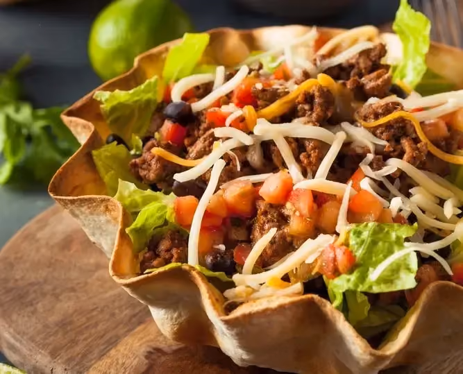 Une grosse tortilla sert de réceptacle aux différents ingrédients comme le boeuf haché, les haricots rouges, les tomates et la salade iceberg.