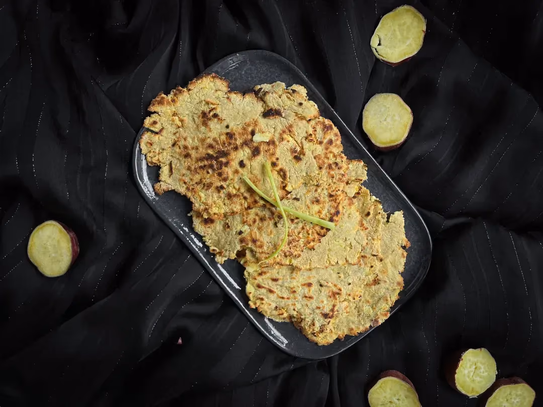 Deux tortillas de patate douce bien grillées sont accompagnées d'un demi citron jaune.