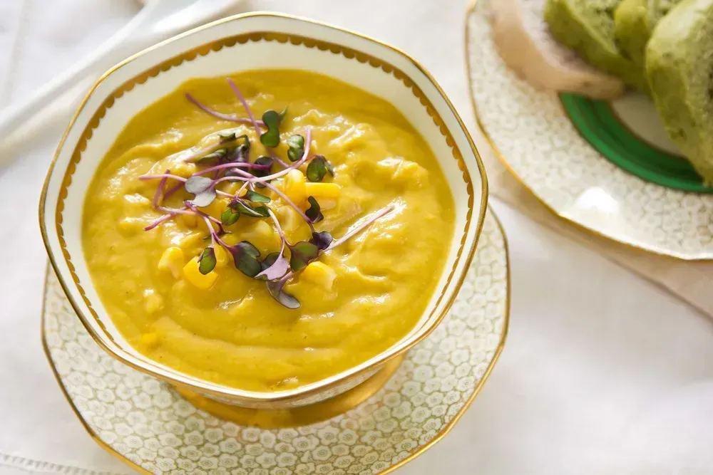 In a beautiful octagonal earthenware soup tureen is a creamy corn soup with chili powder.