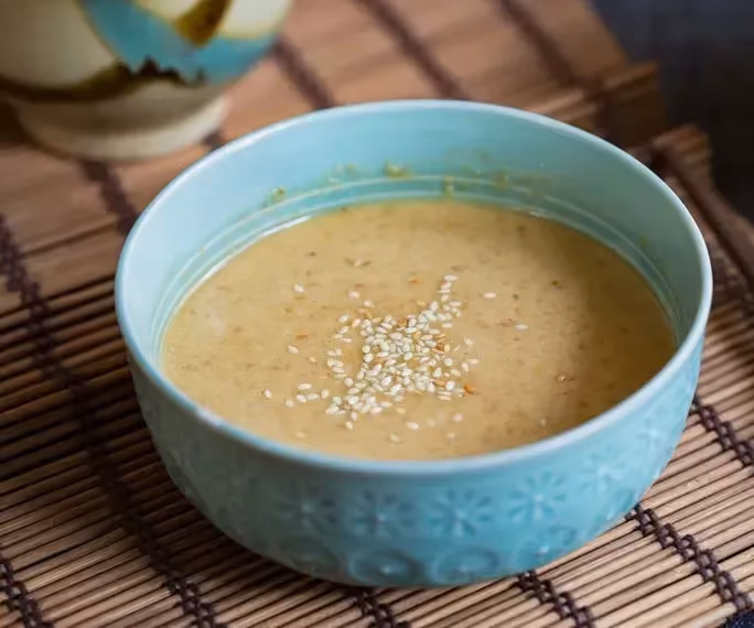 The applesauce vinaigrette is presented in a light blue bowl. The miso gives the vinaigrette this beige color.