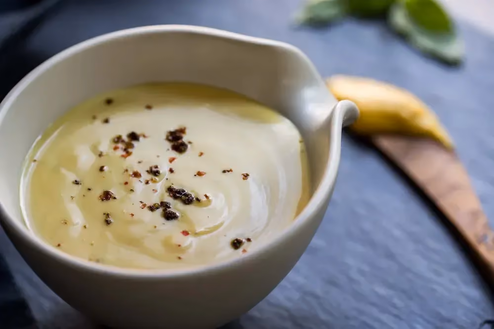 In a white gravy boat is a cottage cheese and balsamic vinegar dressing.