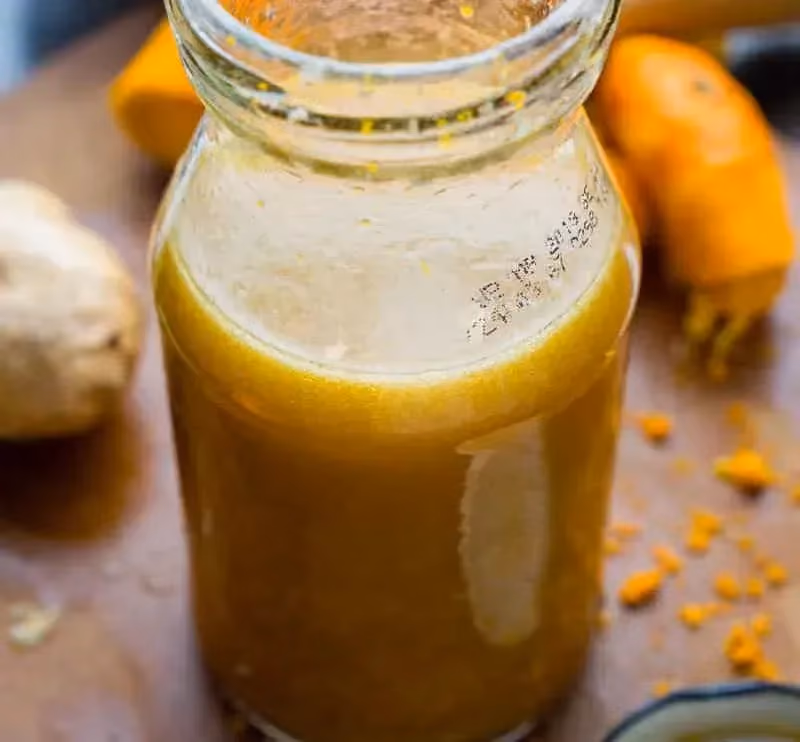 In a glass jar that can be sealed with a lid, the orange and sesame seed dressing shows off its beautiful brown color.