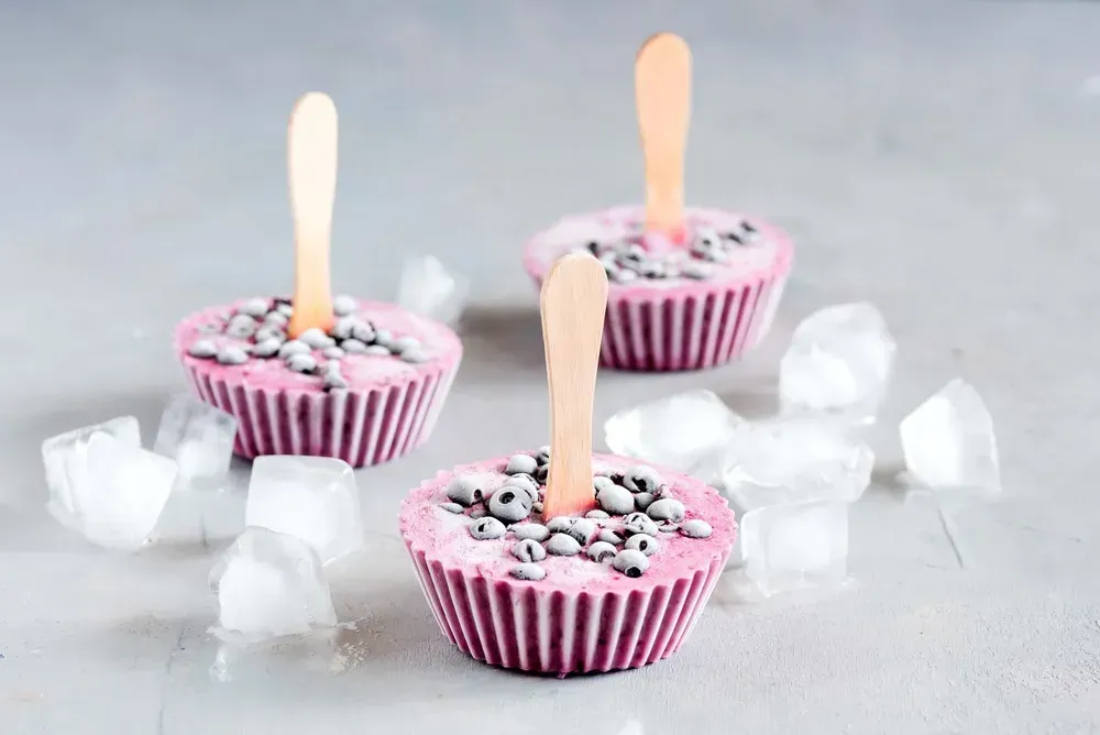 Three frozen yogurts are presented in small muffin molds. Large ice cubes are placed all around.