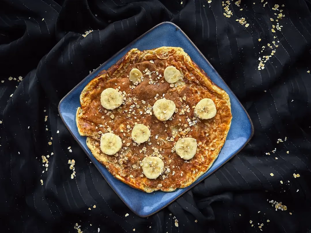 In a large opalescent bowl, the nicely golden pancake is topped with thin banana slices.