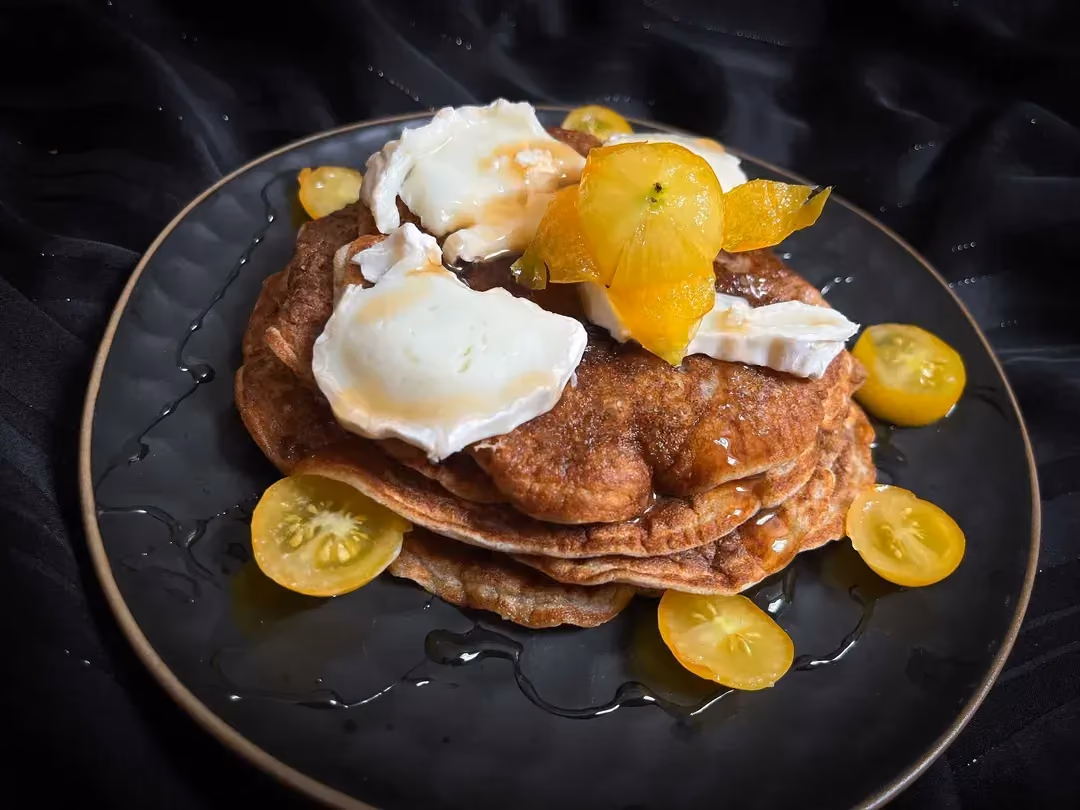 A blue honeycomb-patterned plate serves as a display for buckwheat pancakes with goat cheese and honey.