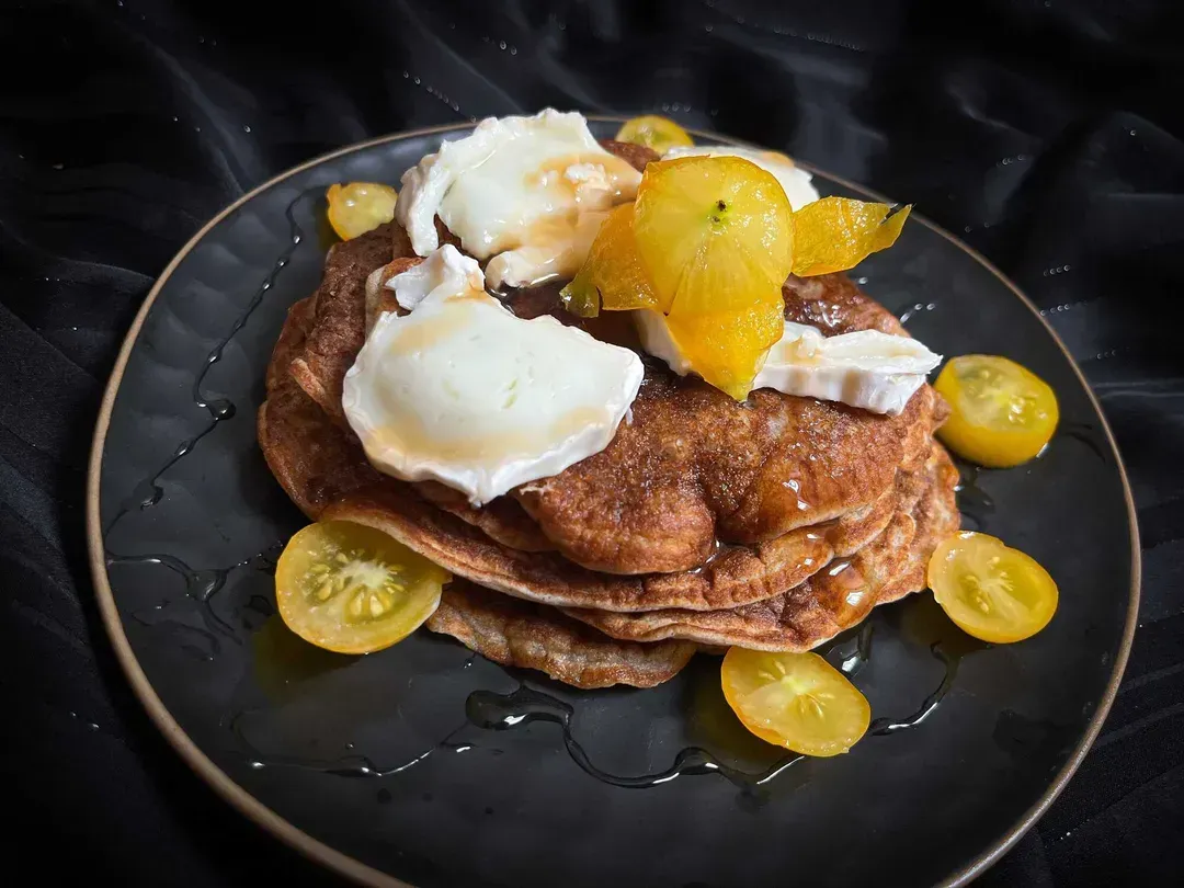 A blue honeycomb-patterned plate serves as a display for buckwheat pancakes with goat cheese and honey.