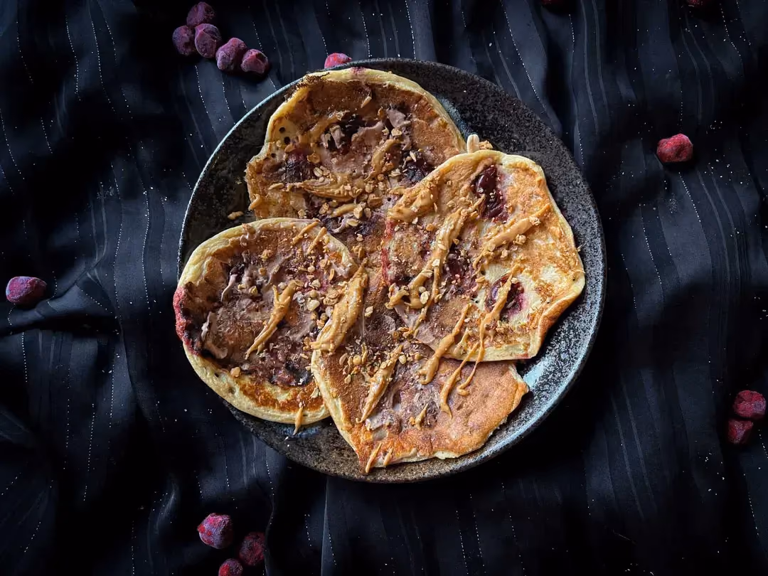 Quatre pancakes protéinés fourrés à la cerise sont présentés au dessus d'un saladier.