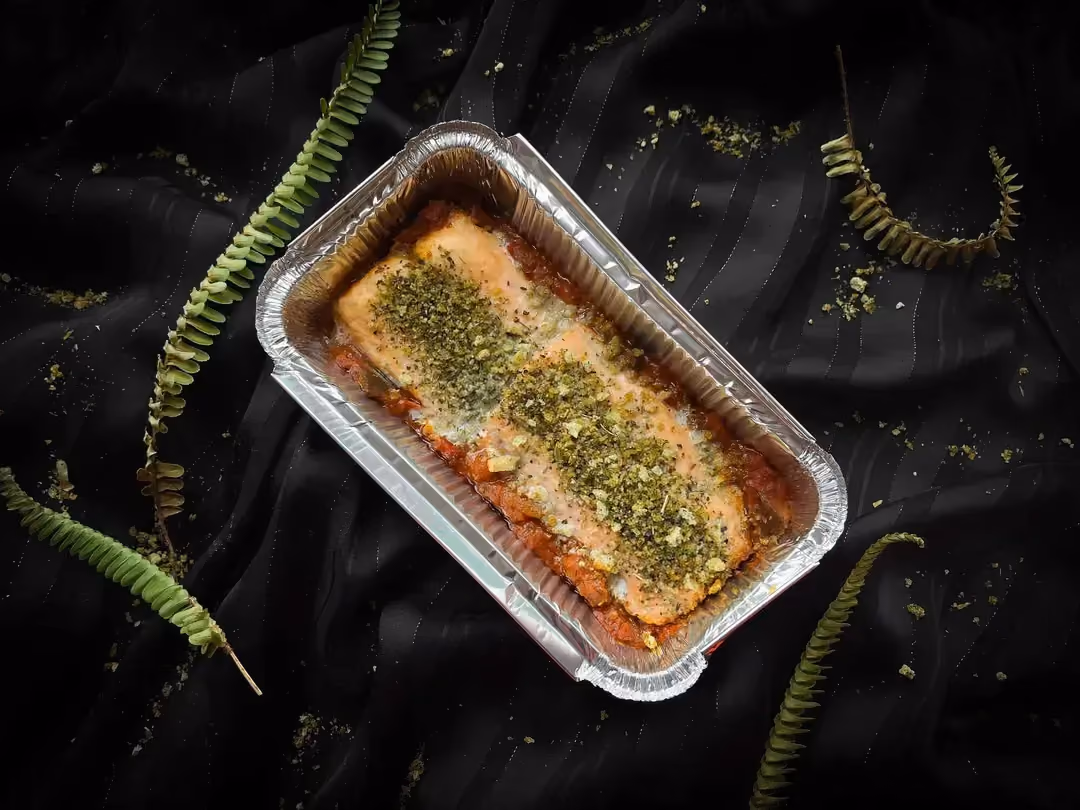 The salmon en papillote with ratatouille is presented in a rectangular aluminum dish.