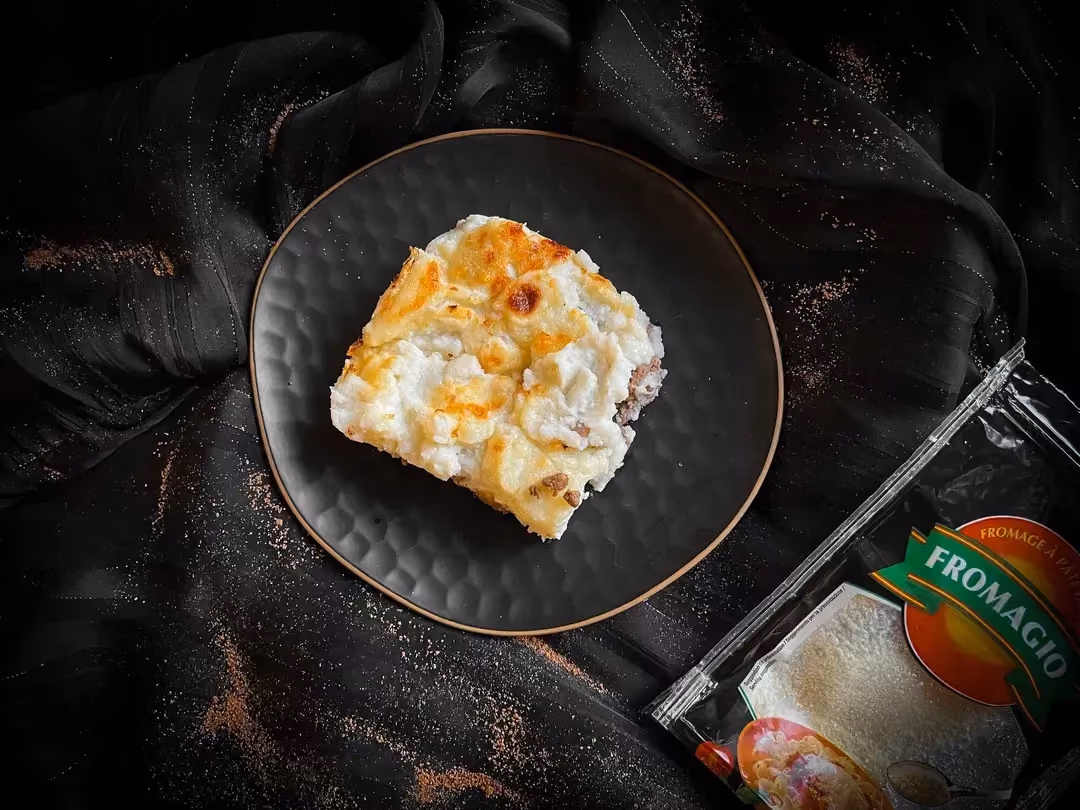 A small blue dish showcases a beautiful serving of cauliflower shepherd's pie topped with Parmesan.