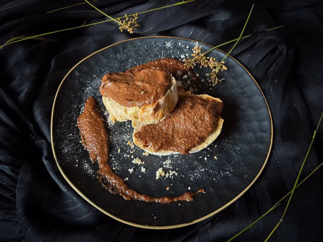 La pâte à tartiner au chocolat, compote de pommes et Nesquick est étalée sur une grosse tranche de pain et sur un pancake.
