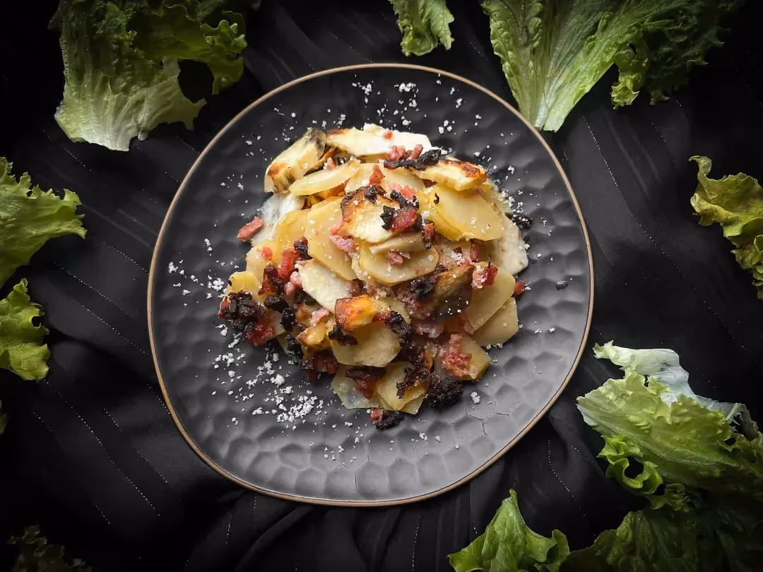 La recette de poêlée de patates douces, pomme de terre, lardons de dinde et crème est présentée dans un petit saladier de couleur bleu alvéolé.