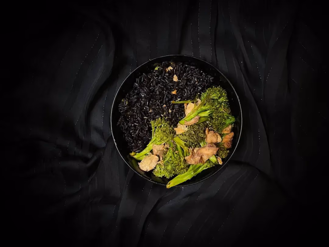 Sur un lit de riz noir, se trouve du saumon coupé en cubes et des brocolis en fleurette.