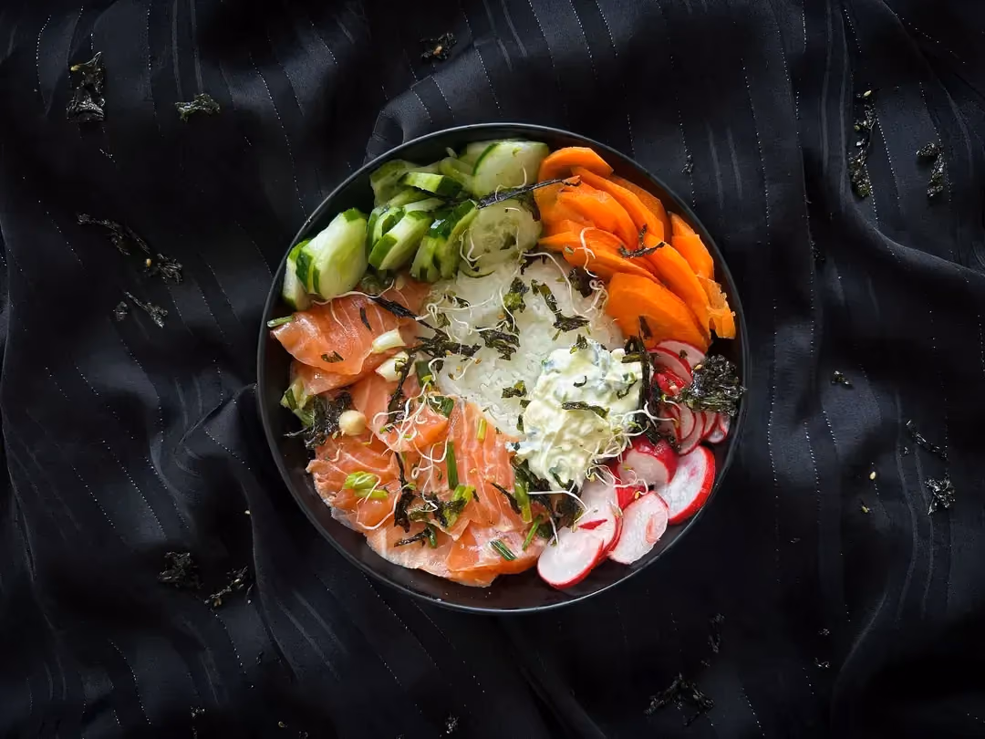 Dans un grand bol, on retrouve tous les ingrédients de ce poke, le saumon coupé en petit bâtonnet, le concombre et les radis coupés en fines lamelles.