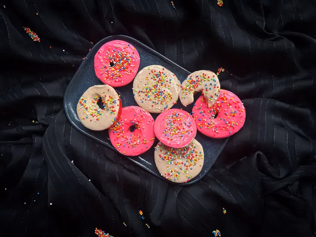 Six slices of festive apples are covered with food coloring and multicolored sprinkles.