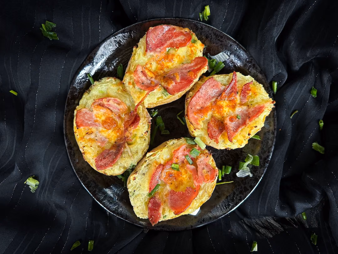 Deux grosses pommes de terre coupées en deux et évidées sont farcies avec du bacon et du cheddar.