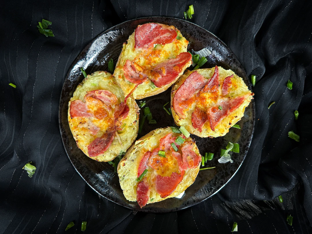 Deux grosses pommes de terre coupées en deux et évidées sont farcies avec du bacon et du cheddar.