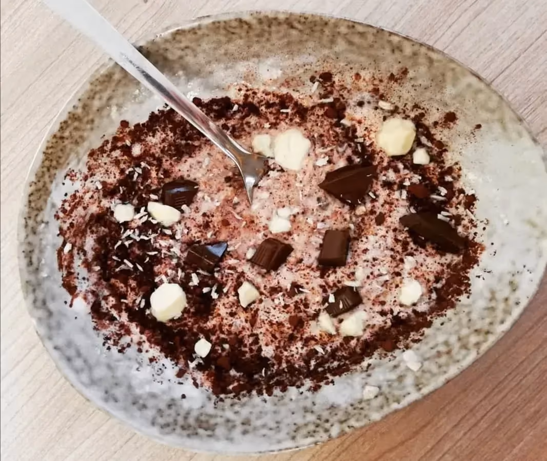 Le porridge au coco et chocolat est présenté dans un plat creux en grès de couleur beige.