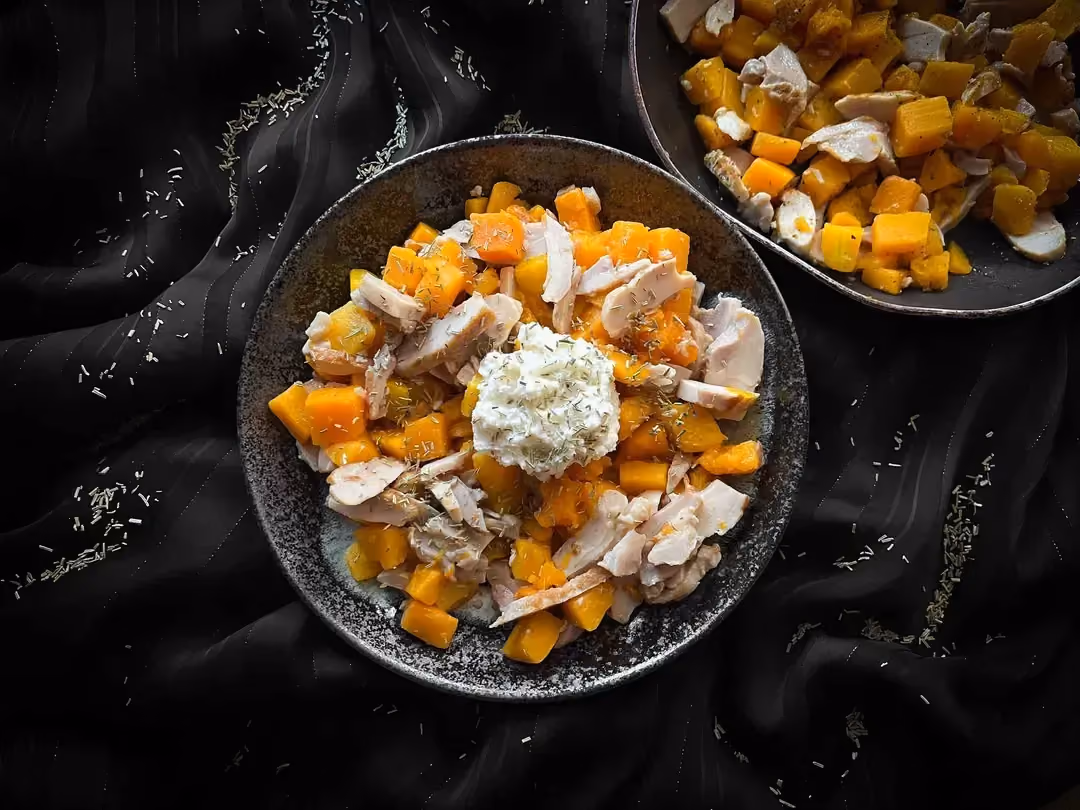 The potimarron, chicken with ricotta and parmesan recipe is presented in two small salad bowls. Parmesan is sprinkled on top.