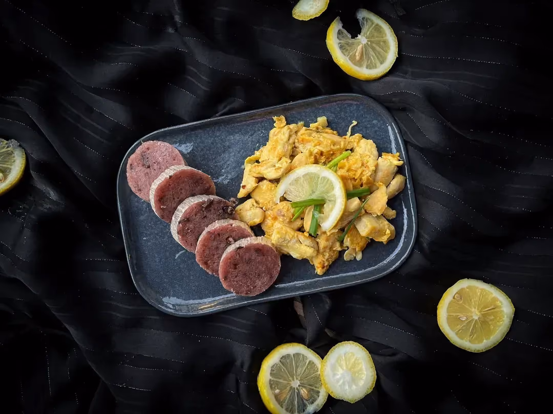 Un petit plat rectangulaire peu profond accueille la recette de poulet à la chinoise au citron. Cinq tranches fines de citron sont autour du plat.