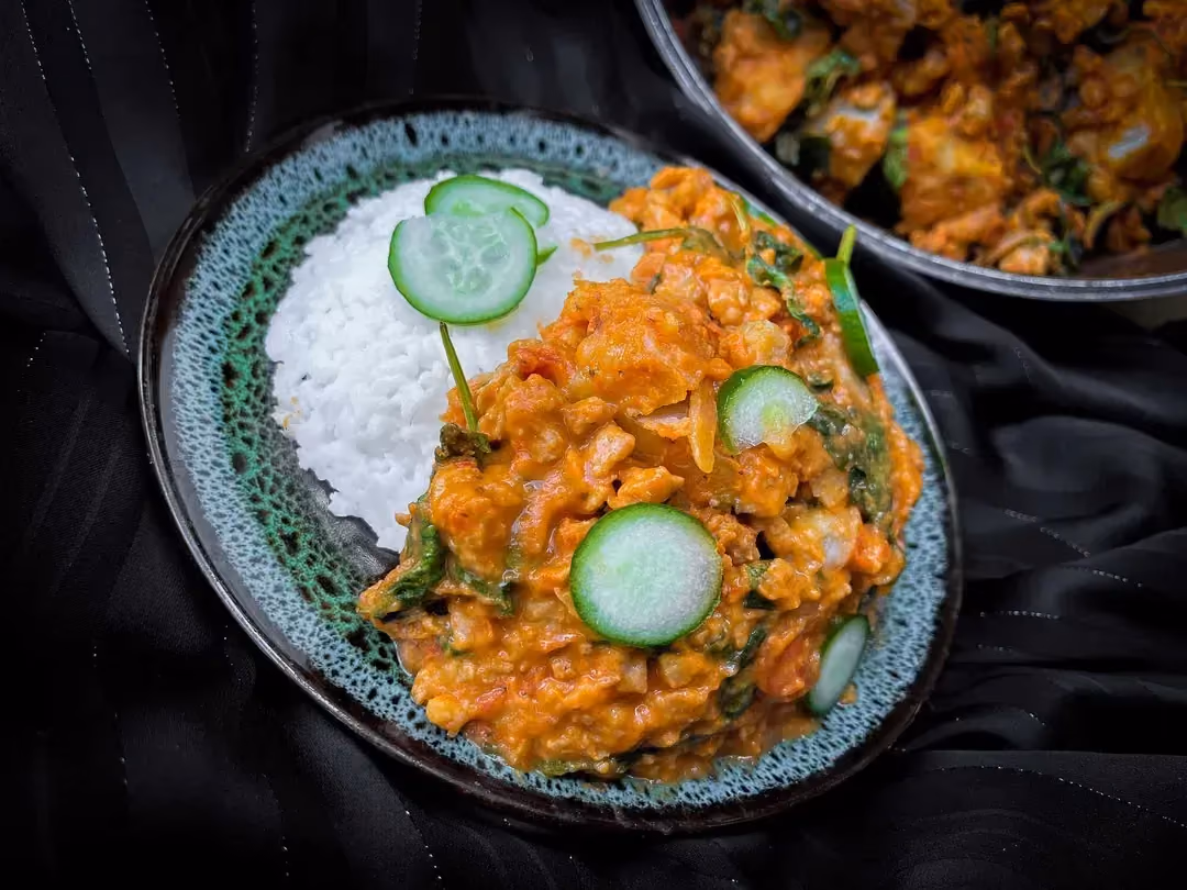Une belle assiette accueille la recette de soja texturées, épinards et patates douces au curry rouge. Six tranches de concombres sont là en déco.