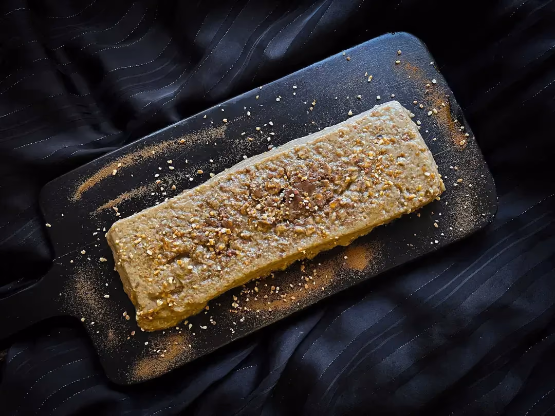 Le pudding à l'avoine et aux céréales est présenté sur une planche à découper de couleur noire.