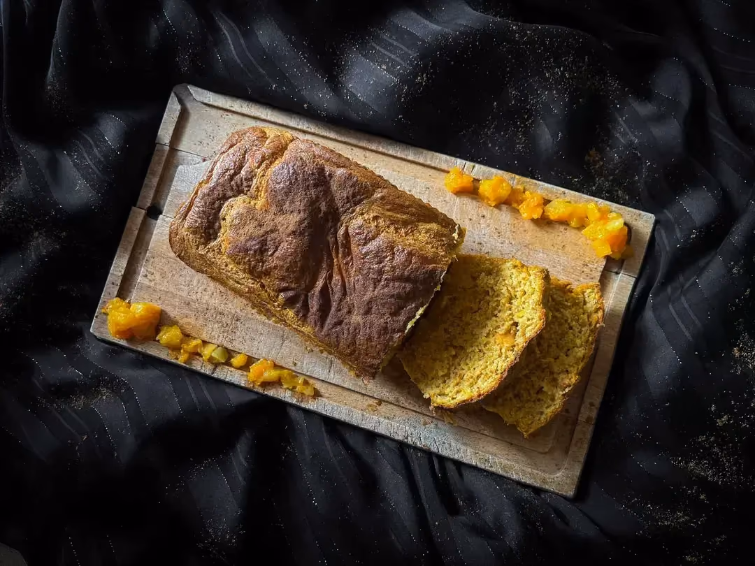 Présenté sur un plateau en bois, se trouve le cake à base de potiron. Deux tranches sont prêtes à être servies.