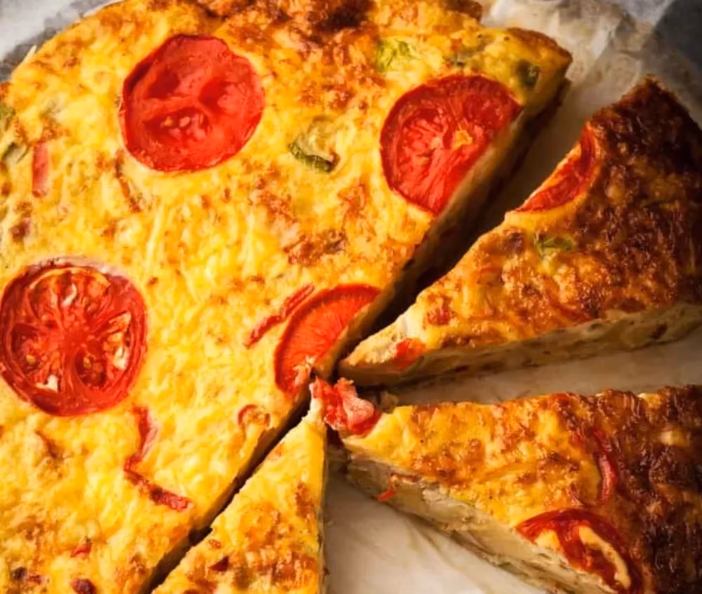 Cette quiche aux tomates sans pâte est hors de son plat de cuisson. Trois grosses parts sont prêtes à être servies.