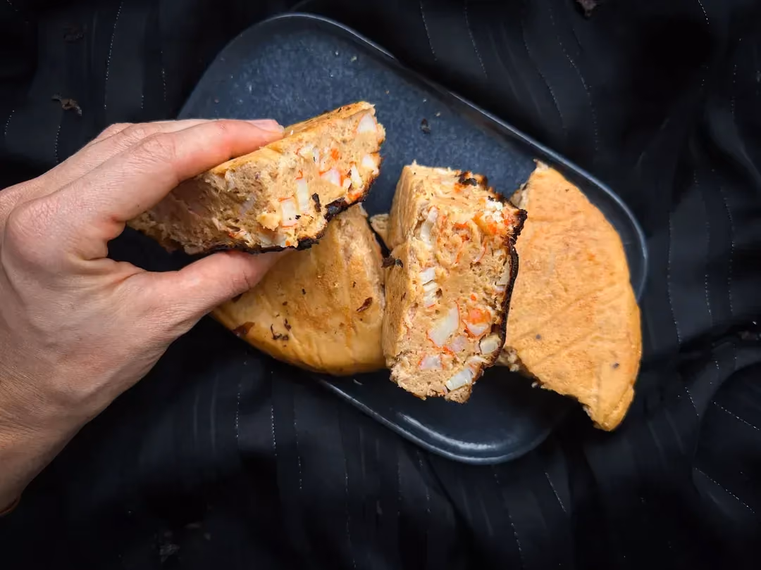Une assiette de couleur bleue posée sur du feuillage accueille trois grosses part de quiche de la mer sans pâte.