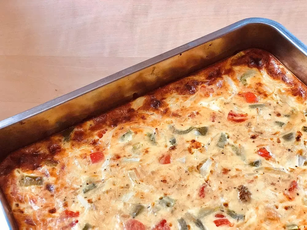 La quiche sans pâte au thon et aux poivrons se trouve dans un plat à gratin transparent.