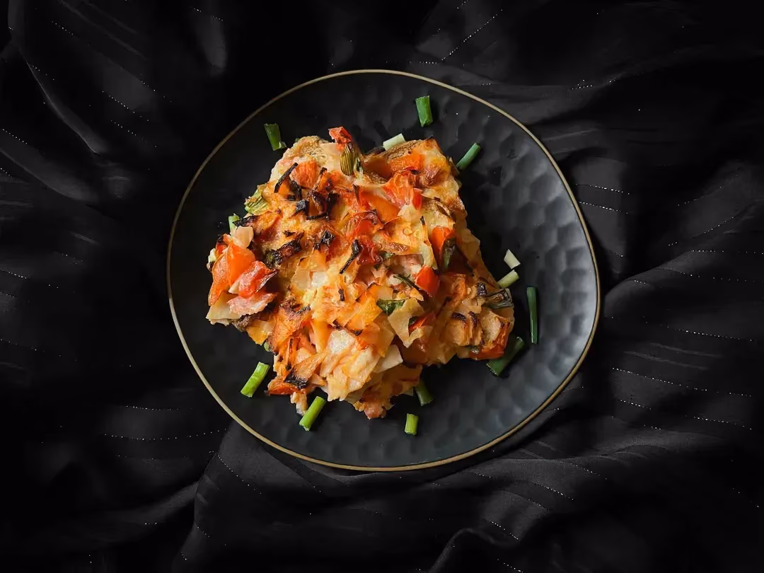 In a blue mixing bowl, there are tomatoes, mozzarella, and turkey breast cut into small cubes, all on a bed of sliced bread.
