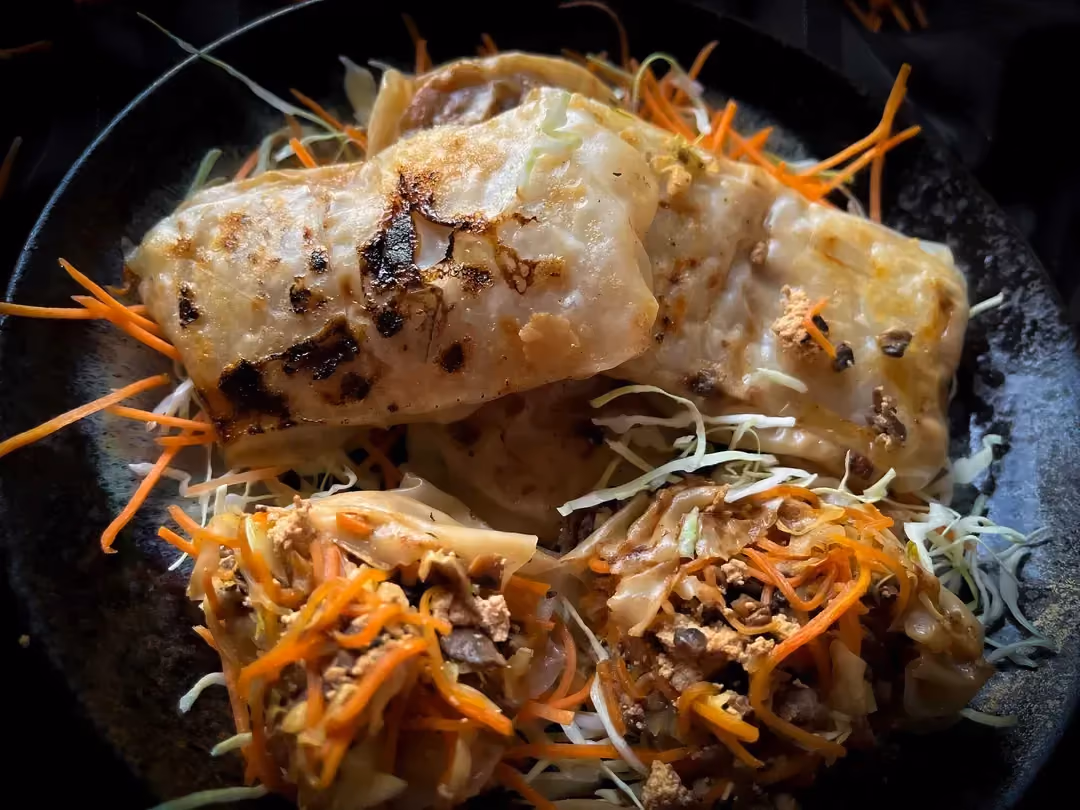 La recette végétarienne de ravioles croustillantes est présentée dans un saladier de couleur bleu.