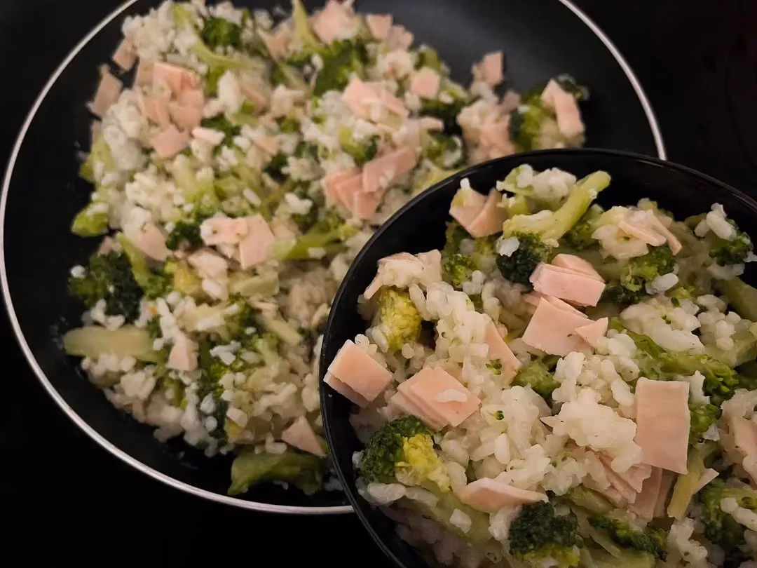 Placed above the pan used for cooking is a beautiful plate containing broccoli and turkey ham risotto.