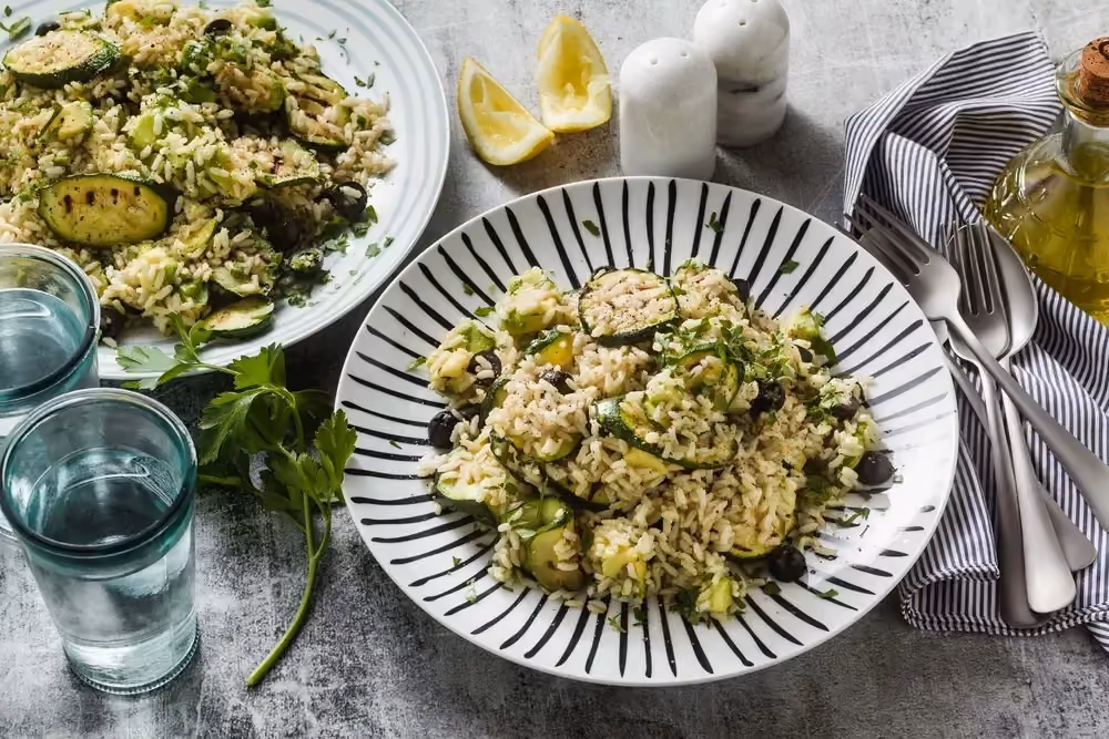 Sur un plan de travail couleur anthrasite, deux belles assiettes sont servis avec le risotto aux courgettes, cabillaud et à la menthe..